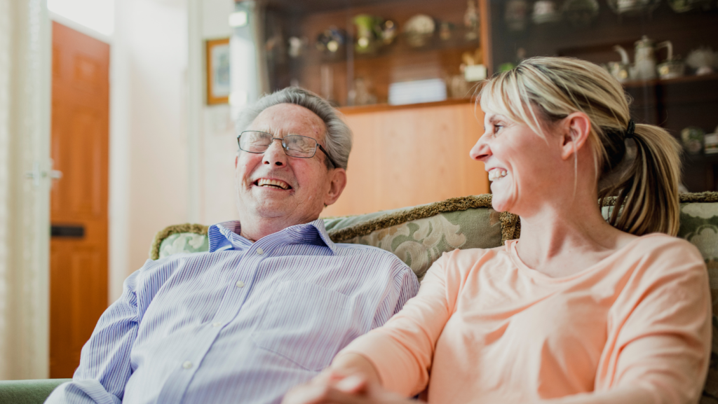 elderly man laughing with female carer