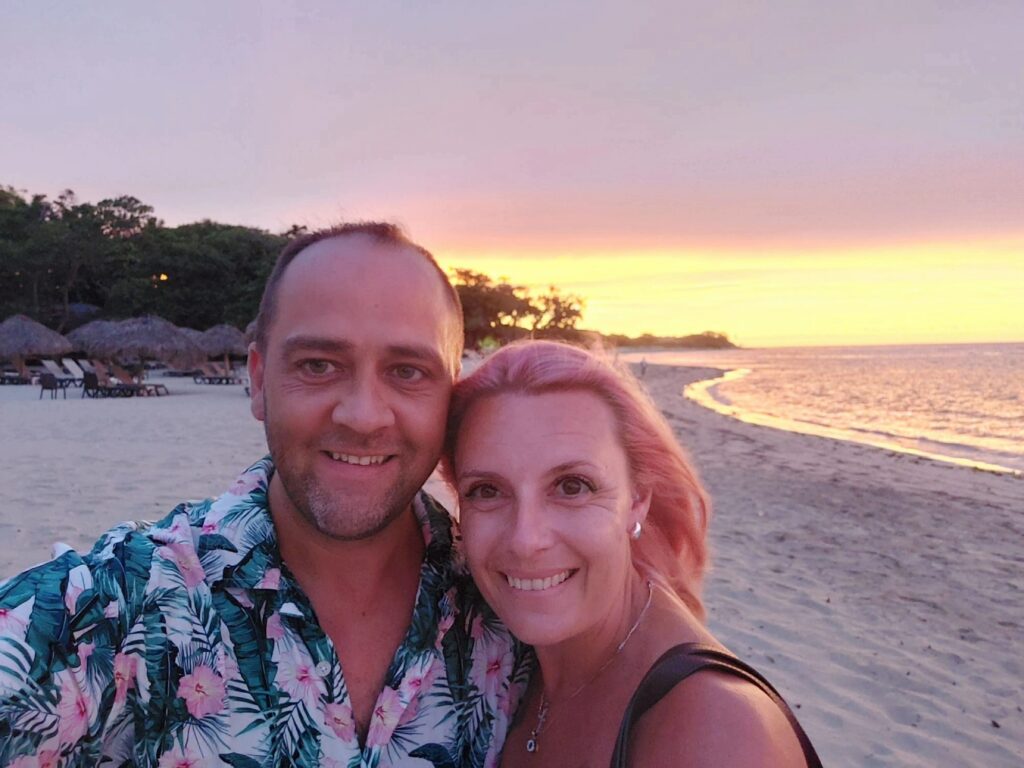 Man and woman in a selfie on beach in front of a sunset